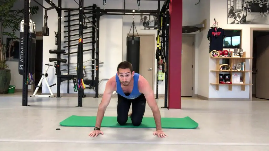 man in tank top kneeling starting to do push ups