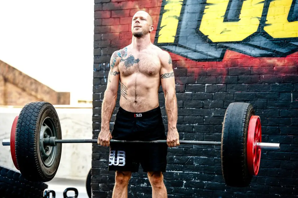 man shirtless deadlifting tires