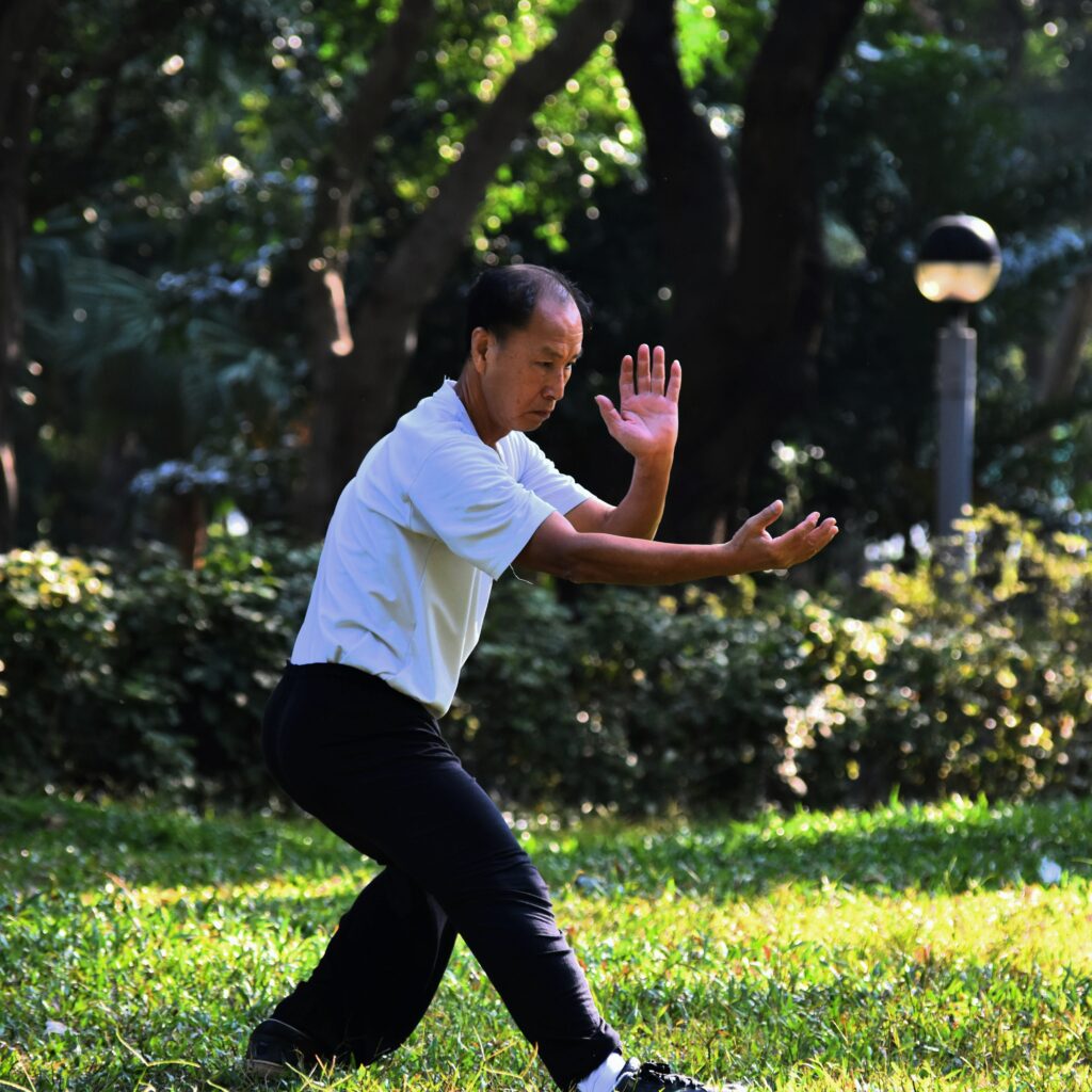 main in white shirt doing tai chi in the park