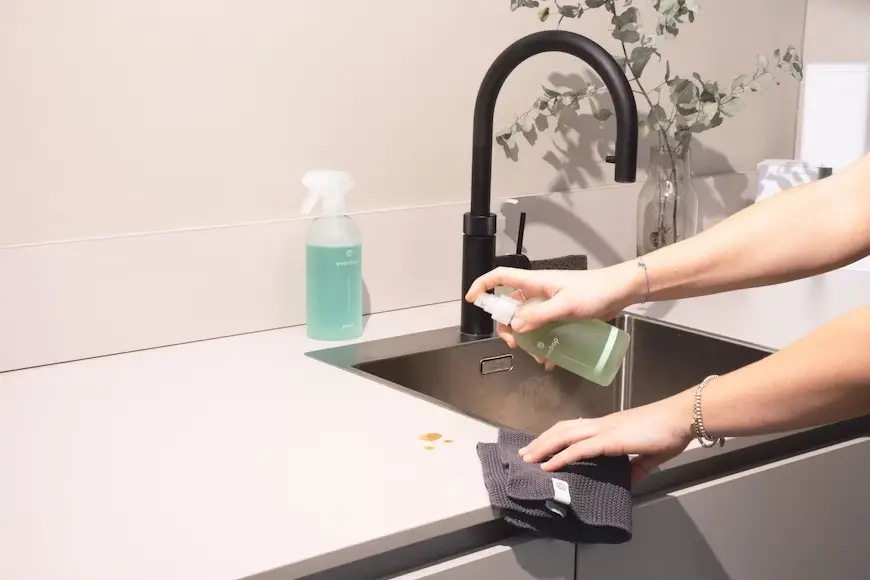 woman spraying down counter while cleaning home